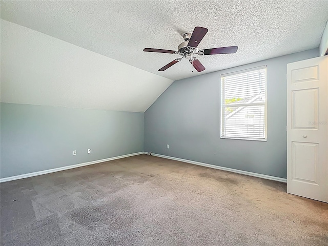 additional living space with a ceiling fan, carpet, baseboards, vaulted ceiling, and a textured ceiling