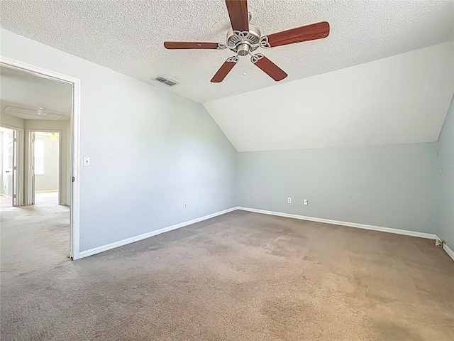 additional living space with lofted ceiling, a ceiling fan, a textured ceiling, carpet, and baseboards