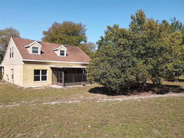 back of house featuring stucco siding, a yard, a sunroom, and roof with shingles