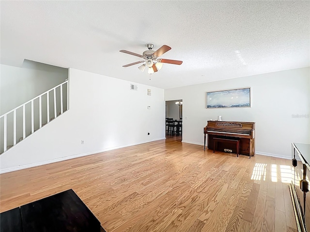 unfurnished living room featuring a ceiling fan, wood finished floors, visible vents, and a textured ceiling