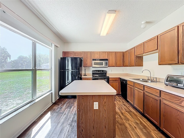 kitchen featuring black appliances, light countertops, dark wood-style flooring, and a sink