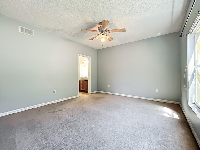 empty room with carpet, a ceiling fan, visible vents, and a healthy amount of sunlight