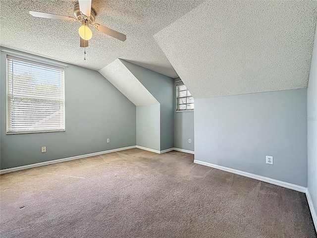 bonus room with a ceiling fan, a textured ceiling, carpet, baseboards, and vaulted ceiling