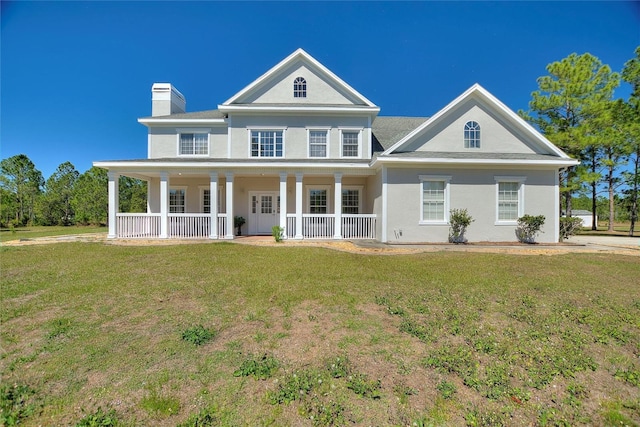 view of front of home featuring covered porch, a chimney, a front lawn, and stucco siding