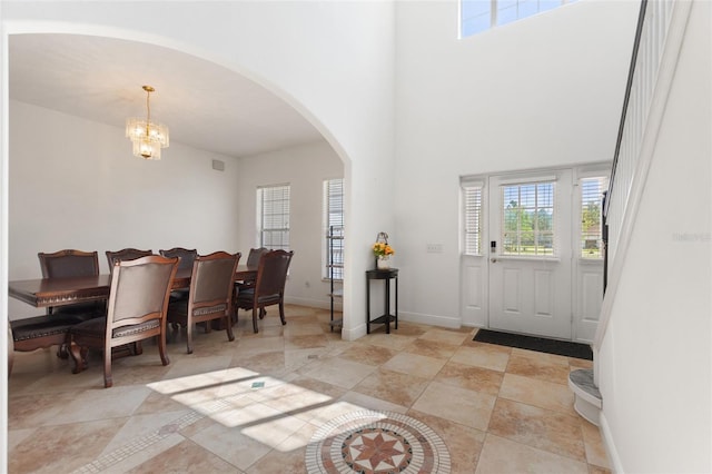 foyer with baseboards, arched walkways, an inviting chandelier, and a towering ceiling