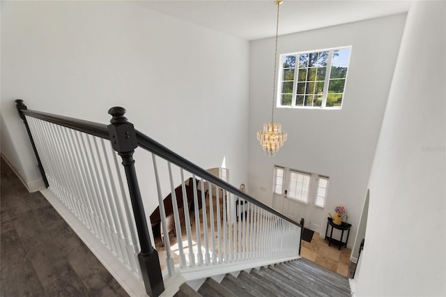 staircase with a chandelier and wood finished floors