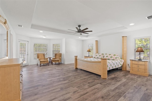 bedroom featuring a raised ceiling, wood finished floors, and baseboards