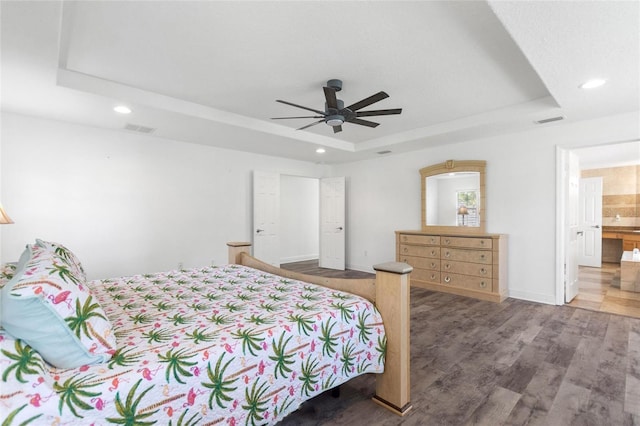 bedroom featuring visible vents, recessed lighting, a tray ceiling, and wood finished floors