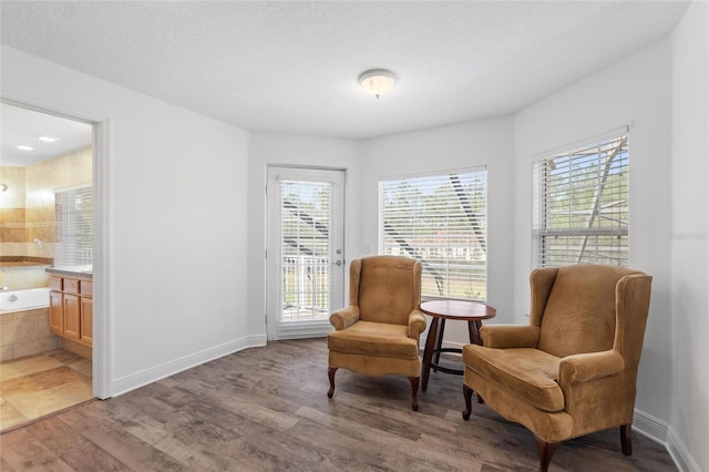 sitting room with a textured ceiling, light wood-type flooring, and baseboards