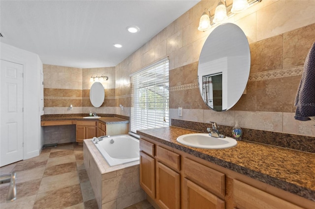 full bath with two vanities, a sink, recessed lighting, tile walls, and a bath