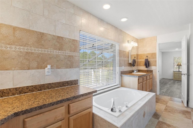 full bath with a bath, recessed lighting, vanity, and tile walls