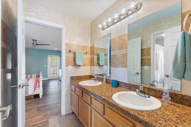 full bathroom with tile walls, ceiling fan, and a sink