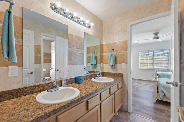 full bath featuring a sink, tile walls, wood finished floors, and double vanity