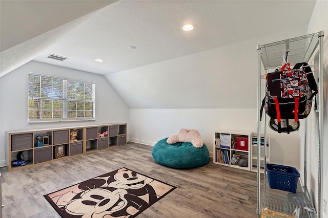 rec room featuring visible vents, lofted ceiling, baseboards, and wood finished floors