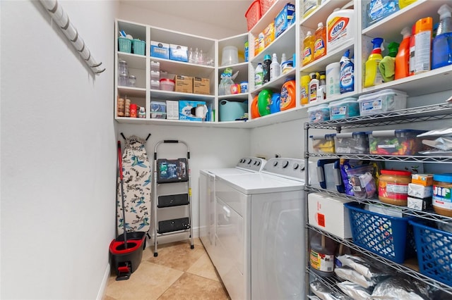 clothes washing area with light tile patterned floors, baseboards, washing machine and dryer, and laundry area