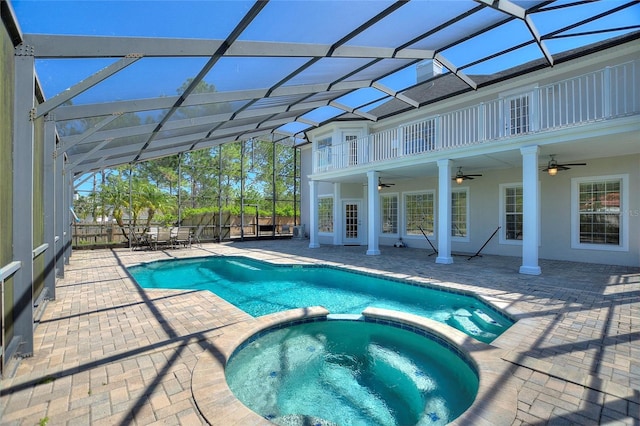 view of pool with glass enclosure, a patio, a pool with connected hot tub, and ceiling fan