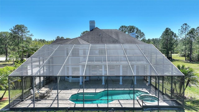 view of swimming pool with glass enclosure, a patio area, and a pool with connected hot tub