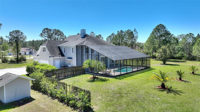 back of house with glass enclosure, an outdoor pool, a yard, and fence