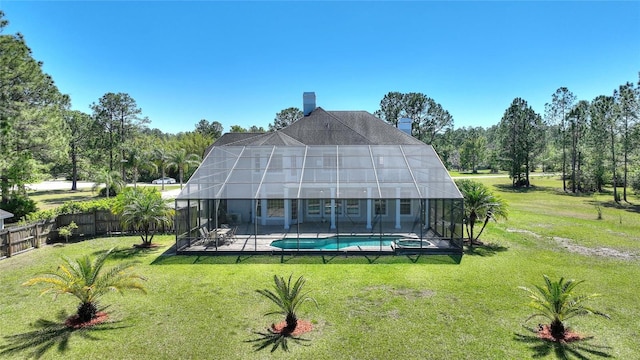 rear view of property with fence, a yard, glass enclosure, an outdoor pool, and a chimney