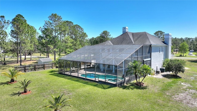 back of property with a yard, an outdoor pool, a chimney, a lanai, and central air condition unit