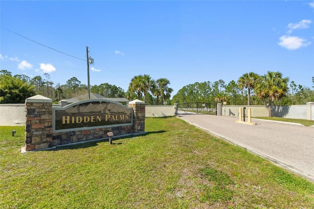 community / neighborhood sign featuring fence and a lawn