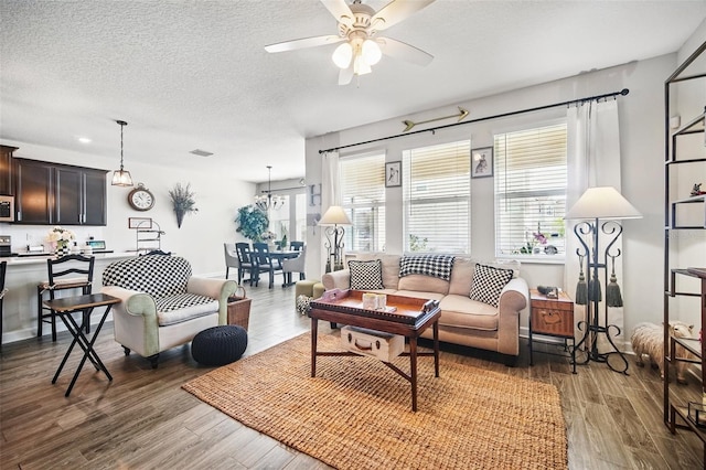 living room featuring ceiling fan, plenty of natural light, a textured ceiling, and light wood-style flooring