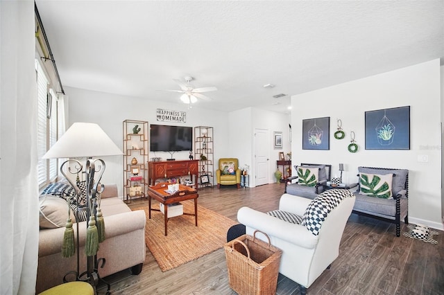 living room with visible vents, ceiling fan, and wood finished floors