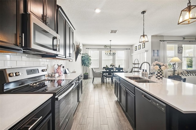 kitchen with a sink, tasteful backsplash, wood finished floors, appliances with stainless steel finishes, and light countertops