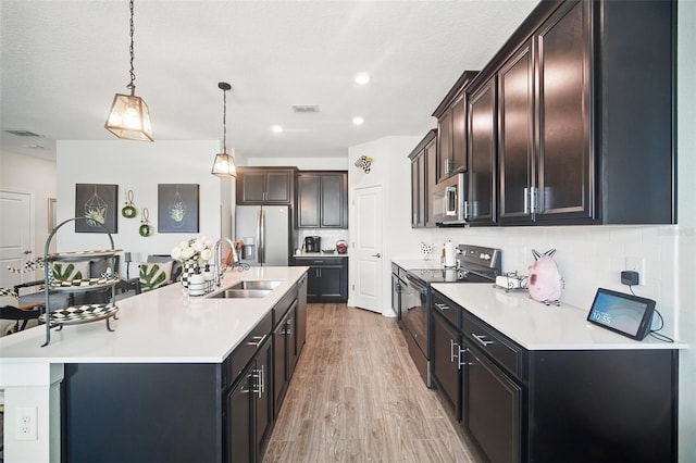 kitchen with backsplash, appliances with stainless steel finishes, light countertops, and a sink