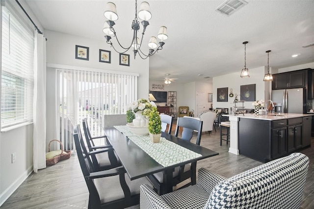 dining room with visible vents, ceiling fan with notable chandelier, baseboards, and wood finished floors