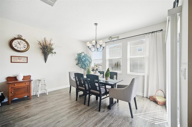 dining space featuring visible vents, baseboards, an inviting chandelier, and wood finished floors