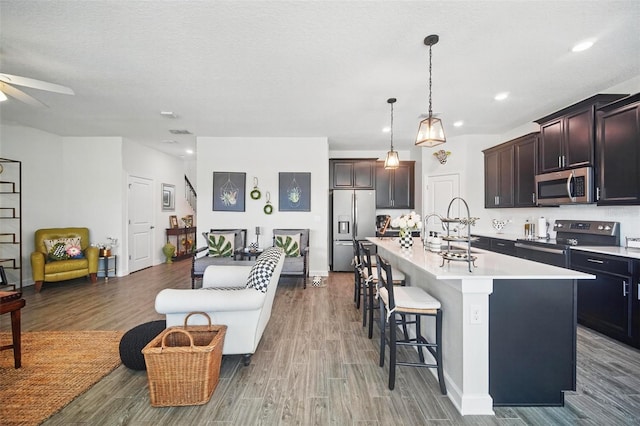 kitchen featuring a kitchen bar, a sink, open floor plan, appliances with stainless steel finishes, and light countertops