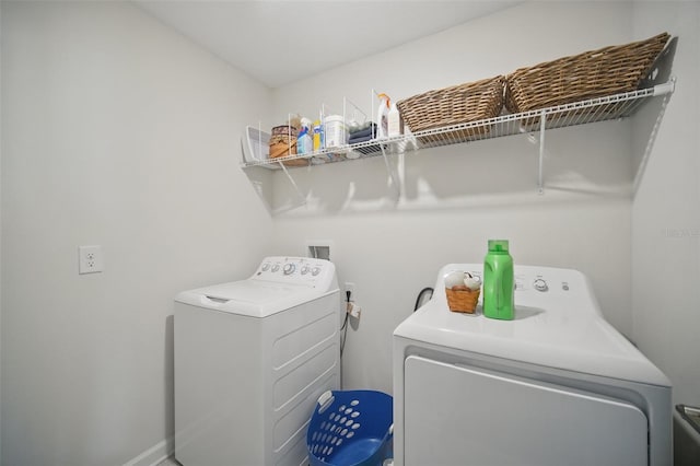 washroom featuring laundry area, baseboards, and washer and clothes dryer