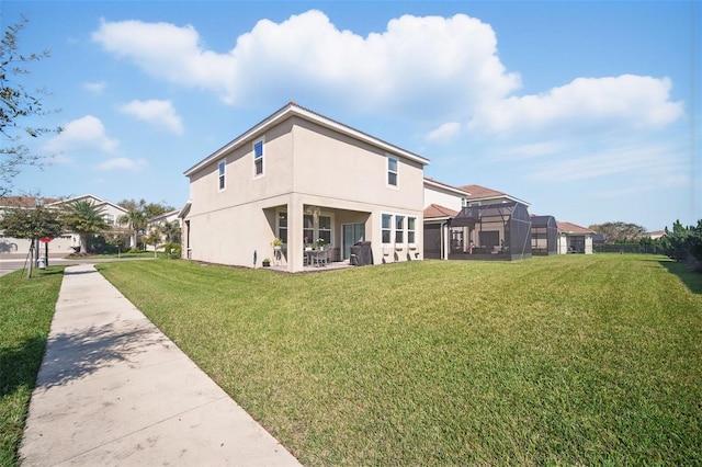 back of house featuring stucco siding, a lawn, and a lanai