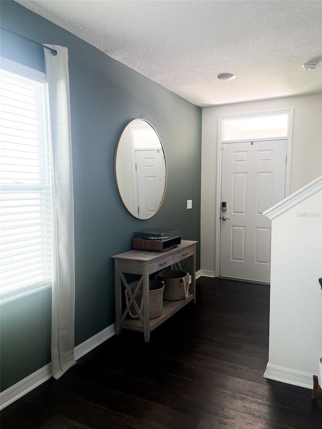 foyer with baseboards, a textured ceiling, and dark wood finished floors