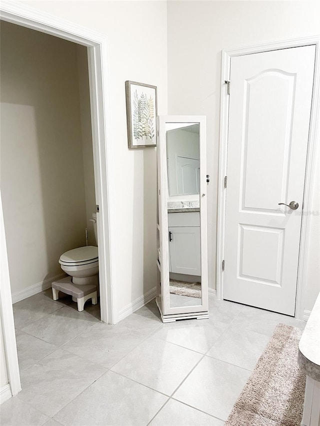 bathroom with tile patterned floors, baseboards, toilet, and vanity