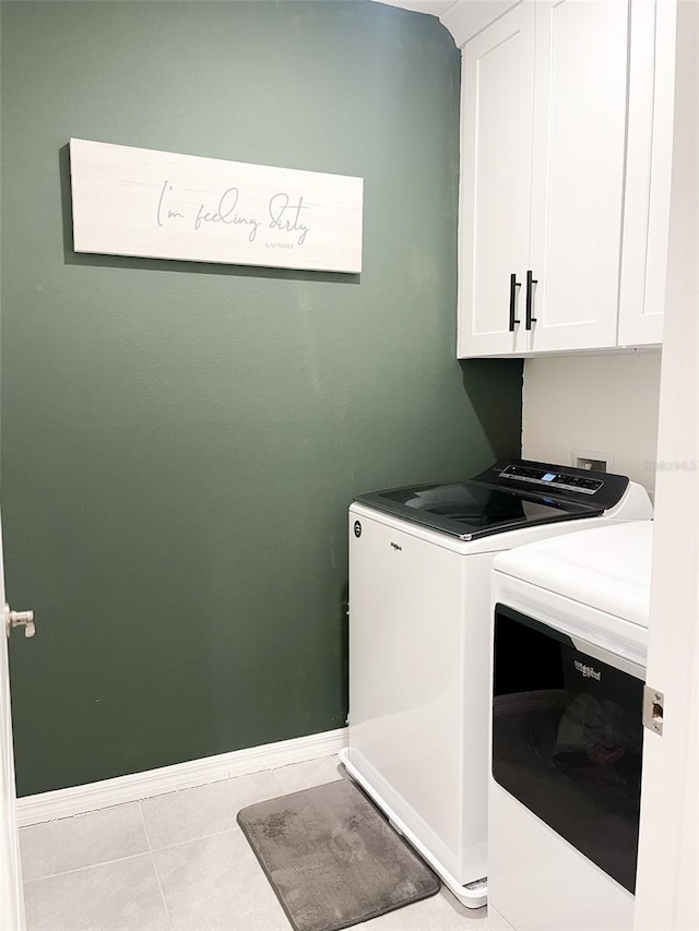 laundry room featuring light tile patterned floors, baseboards, cabinet space, and washing machine and dryer