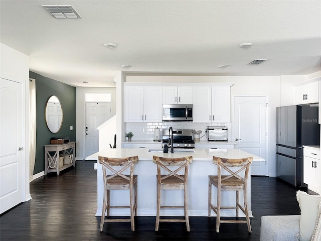 kitchen with light countertops, a breakfast bar area, visible vents, and appliances with stainless steel finishes