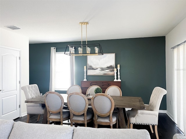 dining space featuring dark wood-style floors, visible vents, baseboards, and an inviting chandelier