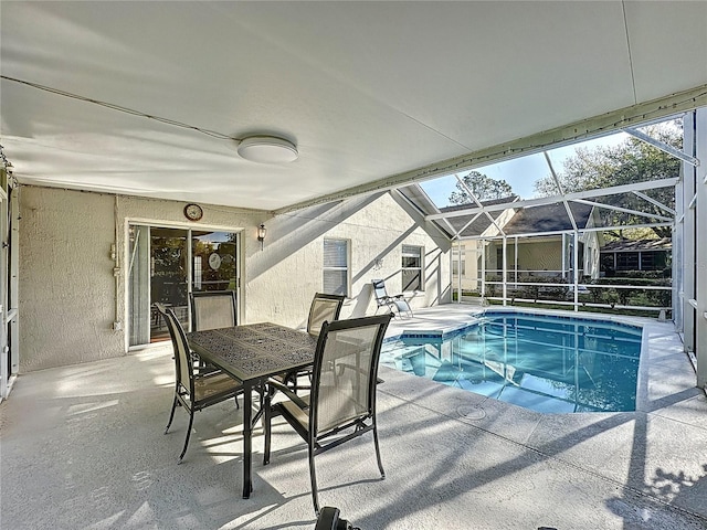 pool featuring glass enclosure, outdoor dining space, and a patio area