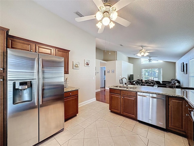 kitchen with visible vents, a ceiling fan, a sink, stainless steel appliances, and lofted ceiling