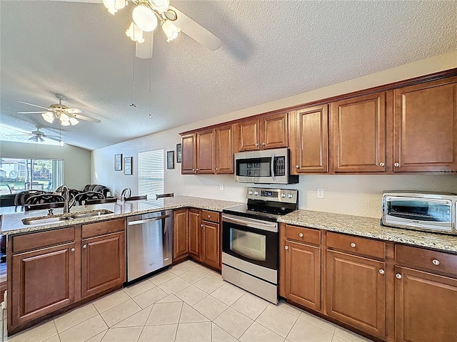 kitchen featuring a peninsula, a toaster, a sink, ceiling fan, and stainless steel appliances