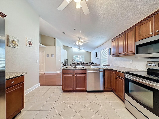 kitchen featuring lofted ceiling, a peninsula, stainless steel appliances, a ceiling fan, and a sink