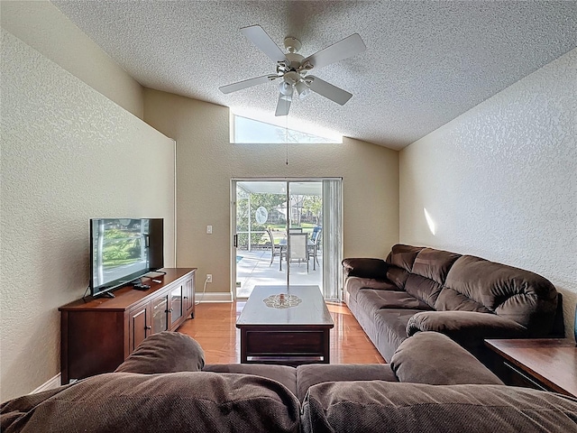 living room with a ceiling fan, a textured ceiling, a textured wall, light wood finished floors, and vaulted ceiling