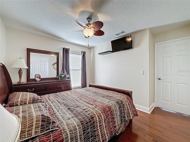 bedroom featuring baseboards, a textured ceiling, a textured wall, and wood finished floors