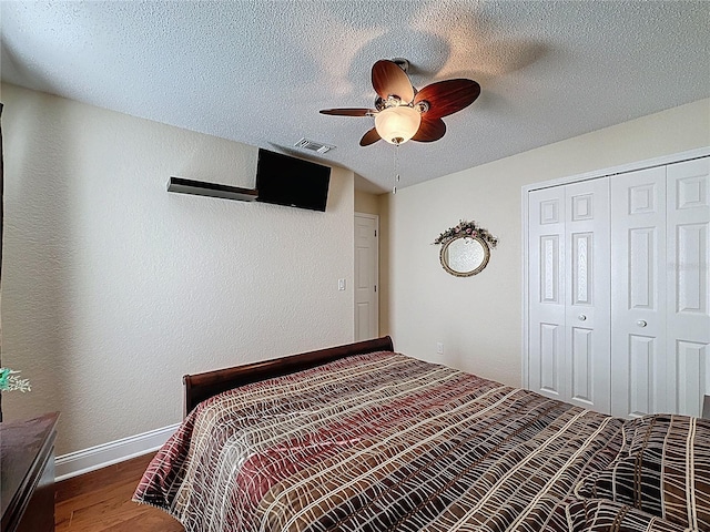 bedroom featuring a closet, visible vents, a textured ceiling, and wood finished floors