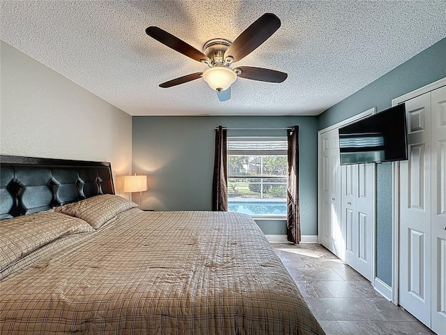 bedroom featuring ceiling fan, stone tile floors, baseboards, and a textured ceiling