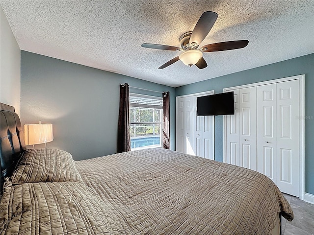 bedroom featuring a textured ceiling, multiple closets, and a ceiling fan