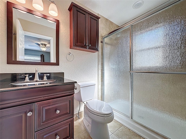 bathroom featuring a shower stall, toilet, a textured wall, tile patterned floors, and vanity