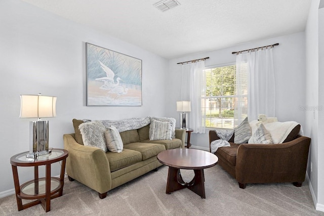 living area with baseboards, visible vents, and light carpet